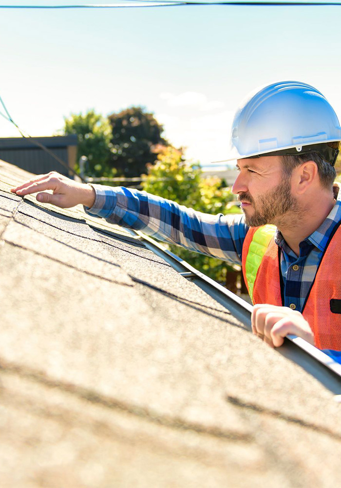 roofing inspector checking asphalt shingles for damage and wear on residential roof